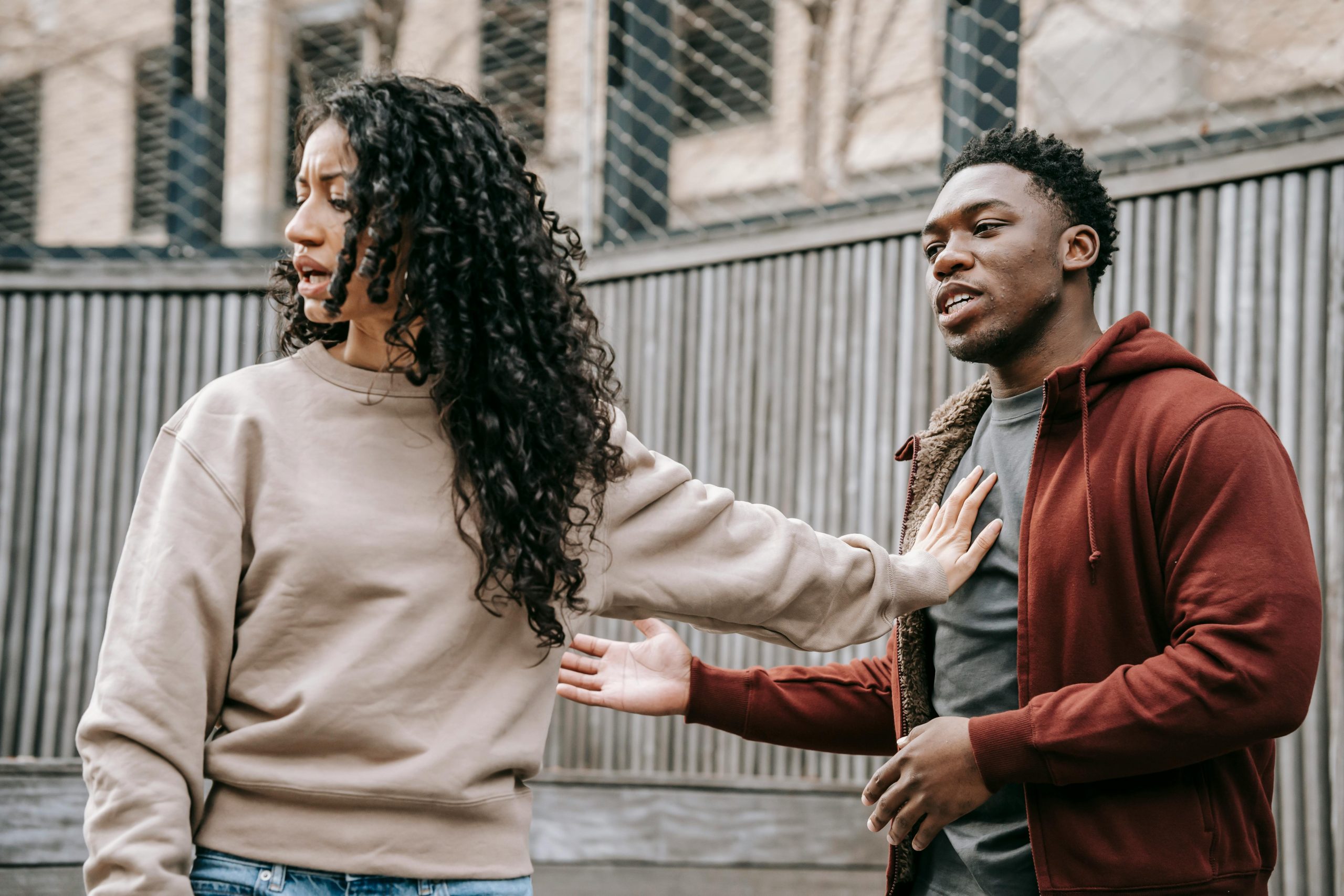 woman pushing her boyfriend back with her hand on his chest during an argument