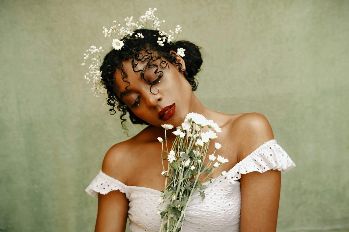 bride wearing full glam makeup, a flower crown, and holding white flowers